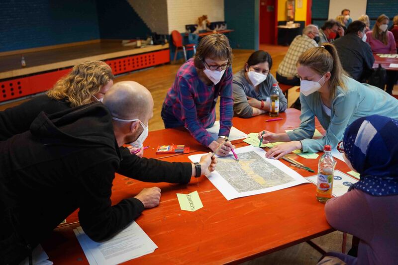 Eine Gruppe von Werkstattteilnehmenden sitzt am Tisch und plant den Parkmeilensommer 2022