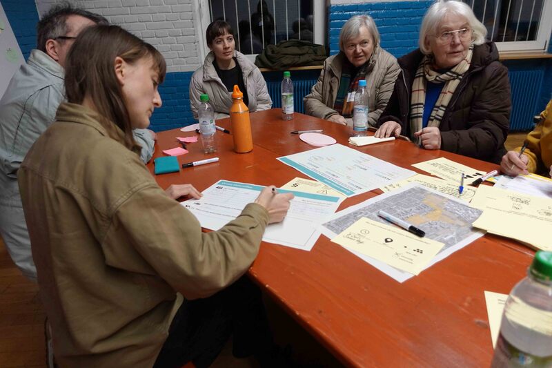Eine Gruppe von Werkstattteilnehmenden sitzt am Tisch und plant den Parkmeilensommer 2022