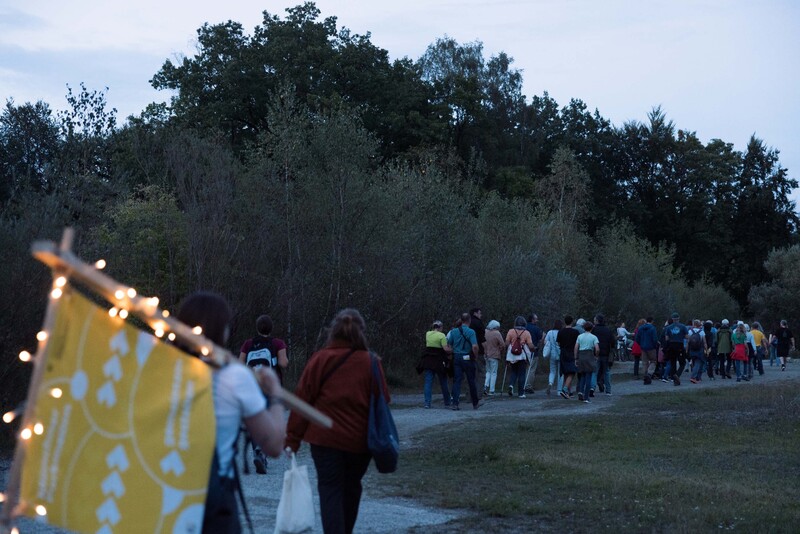 Eine Gruppe von Menschen spaziert in der Dämmerung durch die Parkmeile Trudering-Neuperlach.