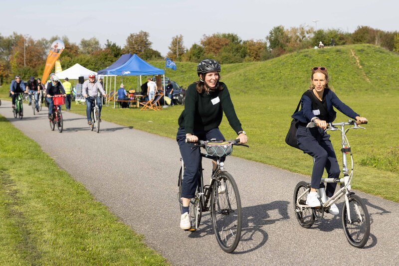 Zwei Radfahrerinnen fahren auf einem Asphaltweg entlang der Parkmeile Trudering-Neuperlach.